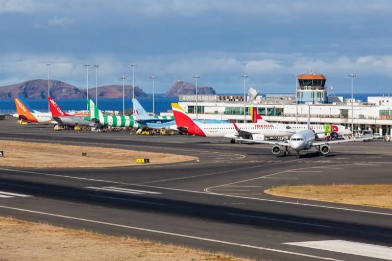 Aviões estacionados no Aeroporto da Madeira, com a torre de controlo e as Ilhas Desertas ao fundo