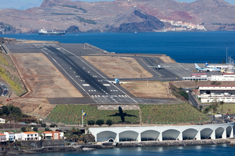 Avião a aterrar no Aeroporto da Madeira, com o mar e as montanhas de Santa Cruz atrás